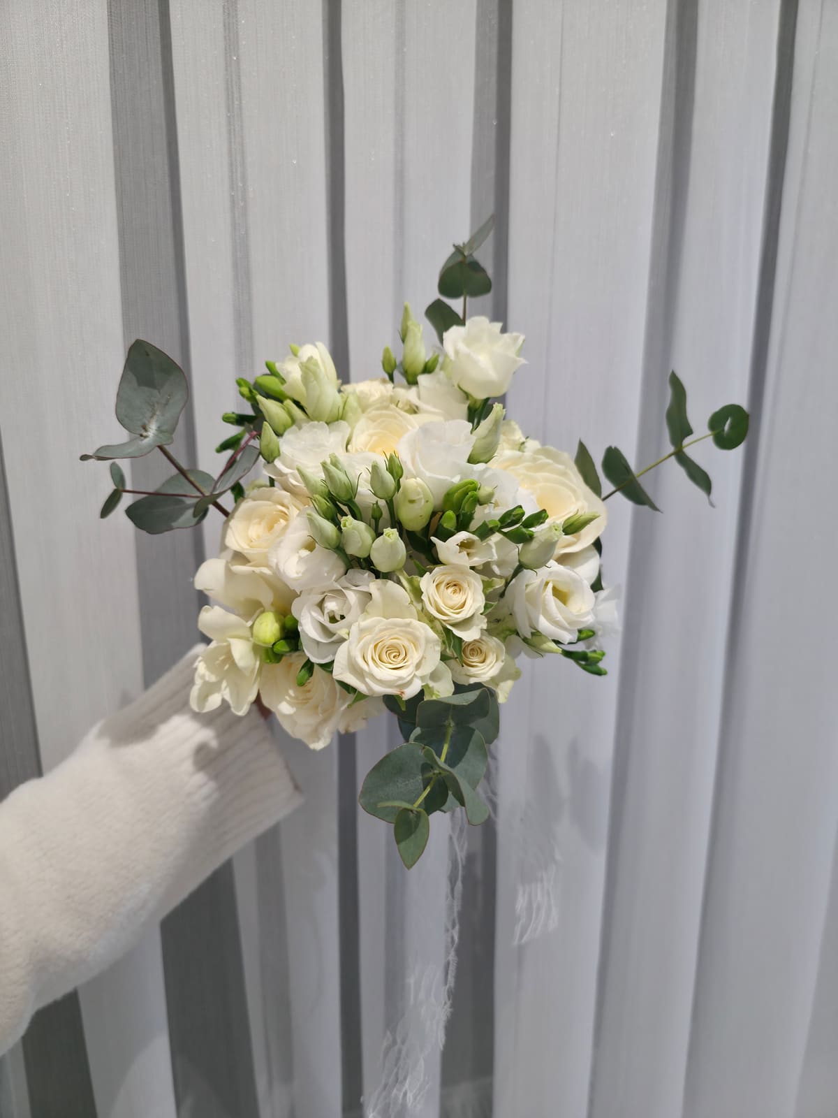 Weißer Brautstrauß mit Freesien, Rosen und Eukalyptus, in der Hand gehalten