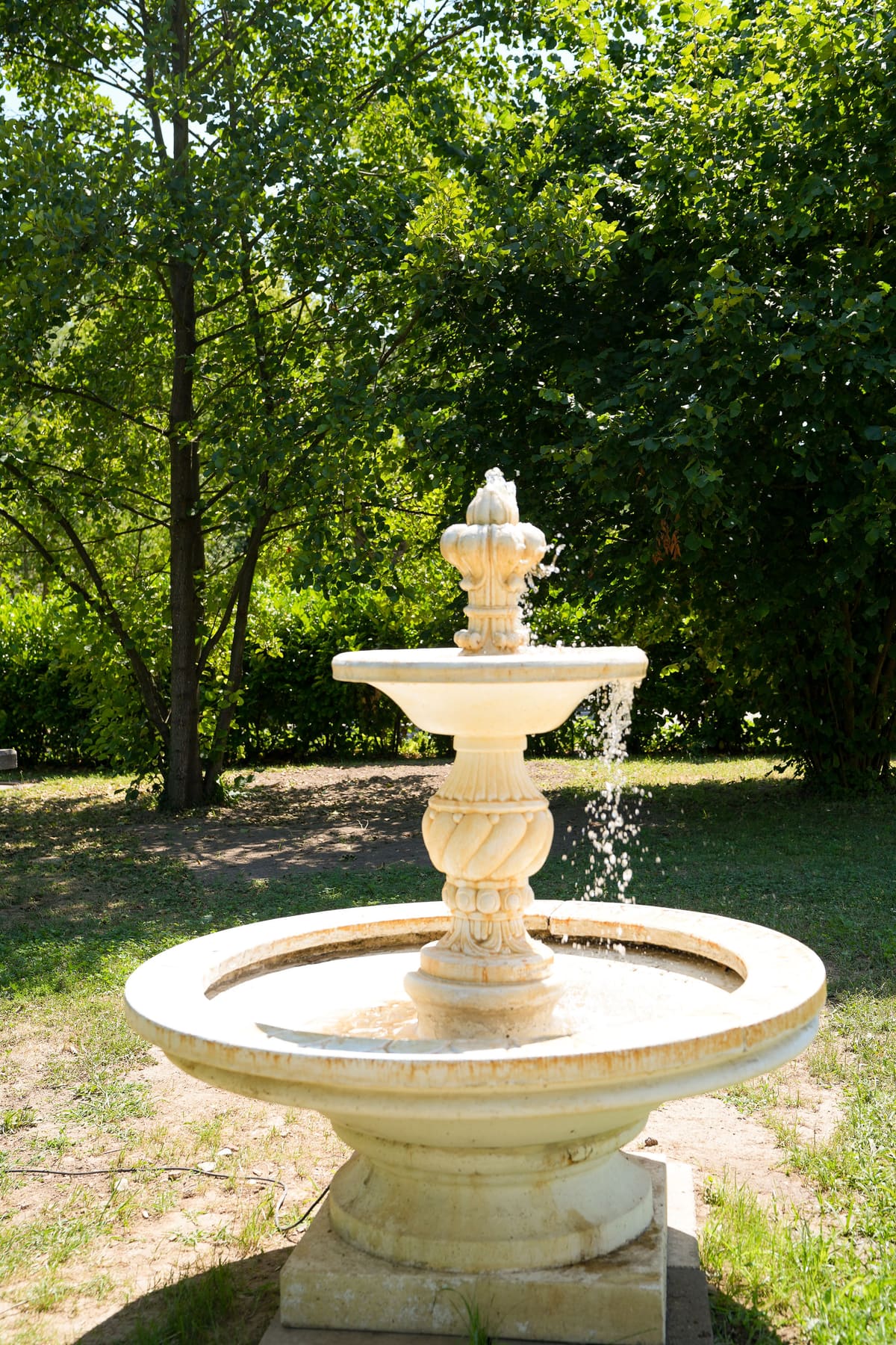 Springbrunnen aus hellem Stein im Garten der Trauungslocation